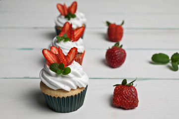 Vanilla cupcakes with strawberry on a light wooden background