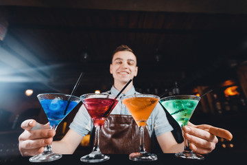 Barman mixes cocktail show with colorful alcoholic cocktails at bar counter.