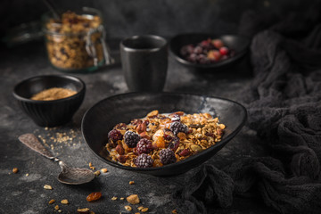 homemade granola (hazelnuts, raisin, dried cranberry, pumpkin, sesame and sunflower seeds) in black bowl.