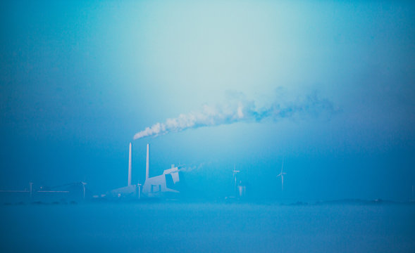 Foggy landscape with a Power Station in the distance.  Smoke rising from the chimneys