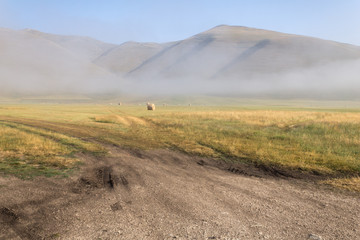 View of Castelluccio di Norcia (Umbria, Italy) upland at morning, with haybales and mist