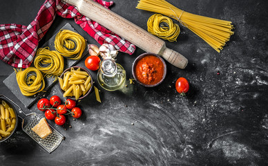 Various types of raw Italian pasta on dark background