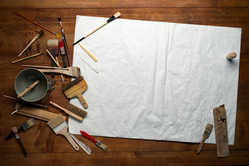 painting still life with paper, brushes and other tools on a wooden background