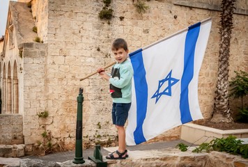 Cute Caucasian boy with a large flag of Israel in his hands.