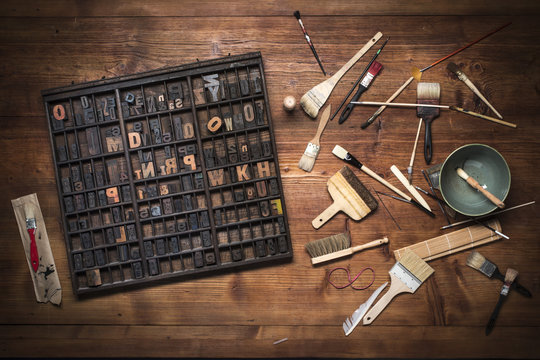 print still life with lettering, brushes and other tools on a wooden background