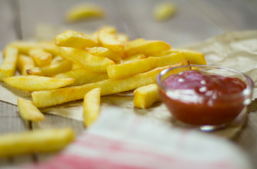 french fries and ketchup in bowl. on paper