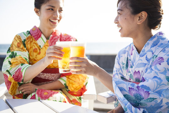 浴衣の女性たちは海辺でビールを飲んでいる