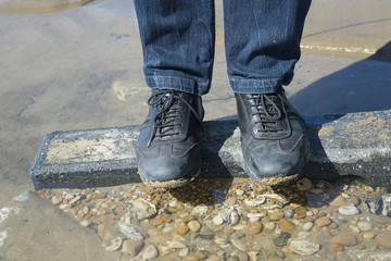 Close up of mens foots on a sea stone