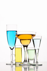 close up view of various alcohol cocktails in glasses on white backdrop