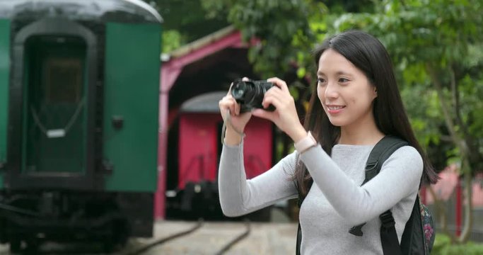Woman travel and taking photo on digital camera at train station