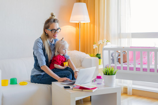 Stay at home mom working on laptop with kid on her lap