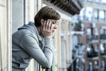 young attractive unhappy depressed lonely woman looking sad on the balcony at home
