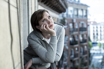 young attractive unhappy depressed lonely woman looking worried on the balcony at home. urban view