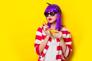 Young girl with purple hair holding lemonade cocktail on yellow background
