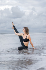 sporty young woman practicing yoga in ocean