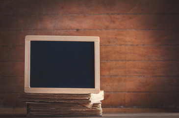 Blackboard and books on wooden table. Image in old color style