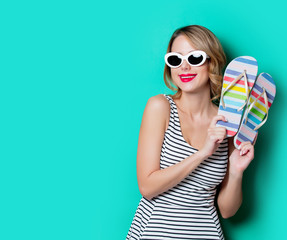 Young woman with flip flops shoes on green background