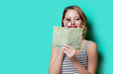 Young girl with map and magnifying glass looking for route.