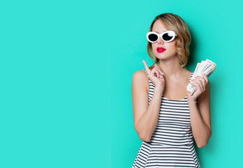Fototapeta premium portrait of a young girl in sunglasses with money on green background