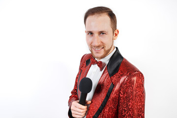 Naklejka premium A young man with a microphone on a white background in a red jacket, leading with a microphone