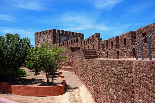 Medieval castle battlements seen with gardens to the left, Silves, Portugal.