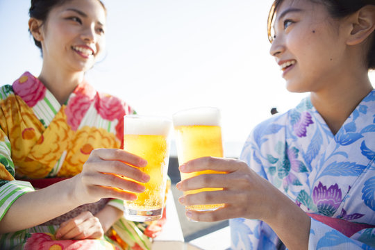 浴衣を着た女性たちは屋外でビールを飲んでいる