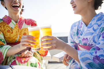 浴衣を着た女性たちは生ビールで乾杯している