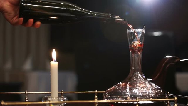 A sommelier pouring red wine into decanter