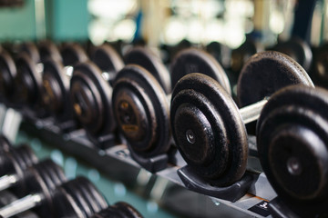 Obraz na płótnie Canvas Rows of dumbbells in the gym with hign contrast and monochrome color tone with bright sunlight. Sport and health bodybuilding concept