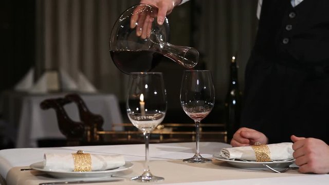 Sommelier pours red wine into a glass from decanter