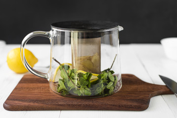 Preparation of ginger tea. Mint, ginger and lemon lie in a glass kettle.