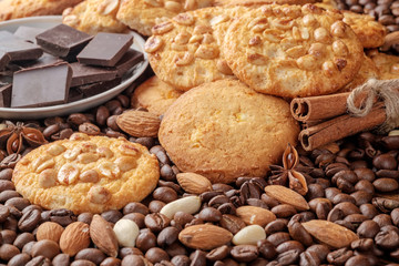 Cookies with peanut, pieces of chocolate, sticks of cinnamon and scattered coffee beans and nuts Closeup view.
