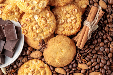 Cookies with peanut, saucer with pieces of chocolate and scattered coffee beans. Top view.