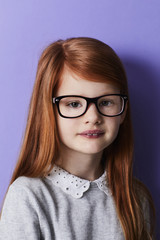 Serious girl with red hair in glasses, portrait