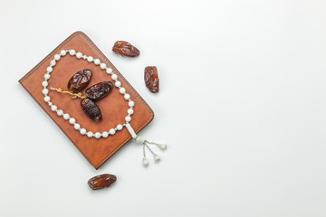 Table top view aerial image of decoration Ramadan Kareem holiday background.Flat lay date with white rosary & the holy book of Koran on modern rustic white wooden at office desk.Free space for text.