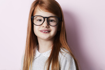 Fototapeta premium Happy redheaded kid in glasses on pink