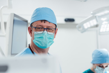 Anesthetist watching patient sleeping in operation room monitoring vital functions