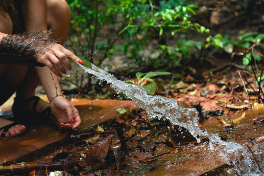 Woman heaving fun with hosepipe splashing water in the jungle