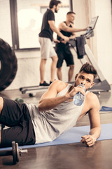 Fototapeta na wymiar handsome sportsman drinking water from bottle in gym
