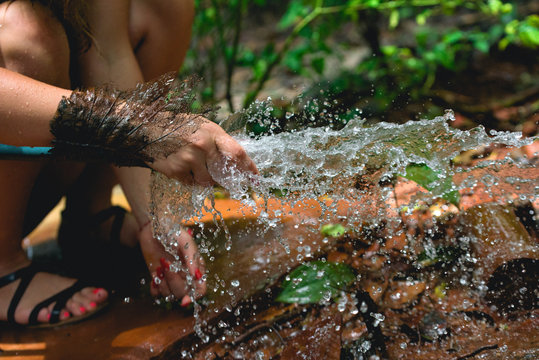 Woman heaving fun with hosepipe splashing water in the jungle