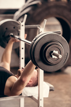 sportsman lifting barbell in gym with weight plates on foreground