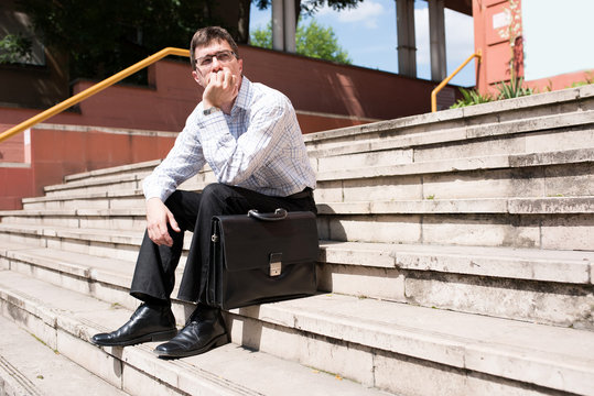 Portrait of a Business man being bored sitting on stairs