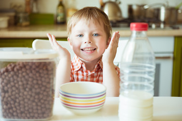 Adorable happy kid boy preparing breakfast or lunch chocolate cereal with milk