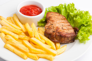 beautiful photo close-up menu of fresh tasty French fries and meat and salad on a plate on a white background