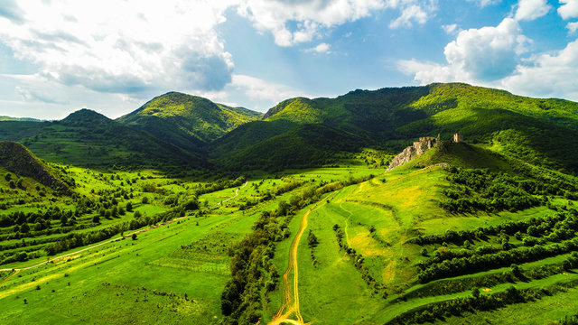 Aerial view of Coltesti Fortress in Transylvania, Romania on a sunny spring day with green hills around and beautiful blue sky with clouds