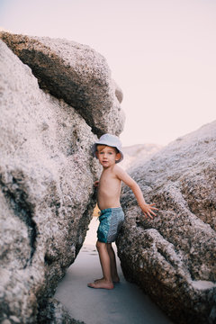 Boy standing between big rocks at beach