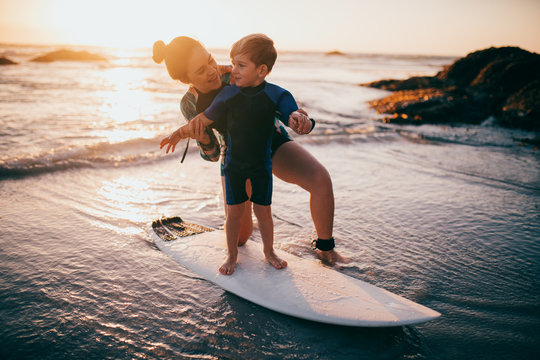 caucasian mother and son practicing surfing