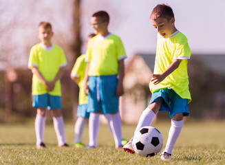 Boy kicking football on the sports field