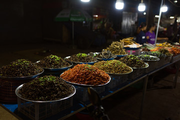 Cambodian night street food market with many kinds of insects, spiders and worms for sale 
