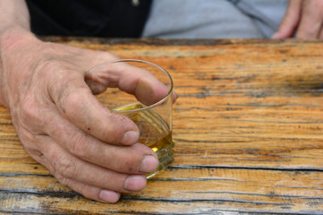 Obraz na płótnie Canvas Man's hand holding glass of good, old plum brandy